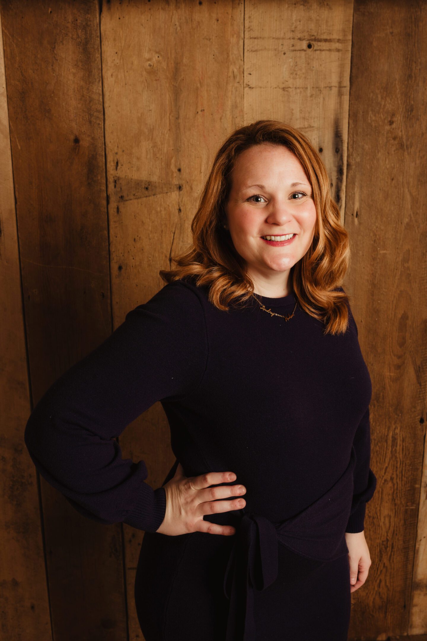 C.MariePhotogrpahyKimber_Business2025-23 A woman standing in front of wooden wall.